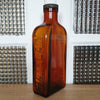 Grand flacon de médicament en verre moulé ambré des Laboratoires J.L. Châtelain - Hello Broc